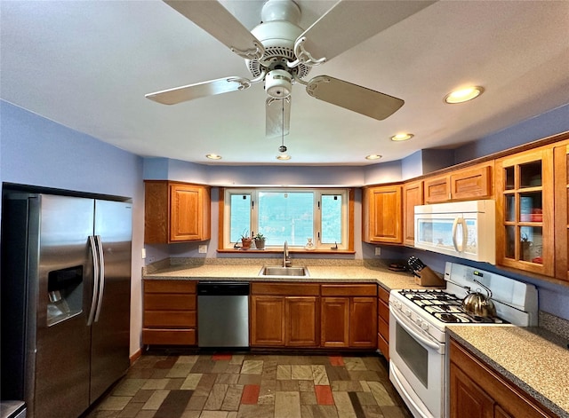 kitchen with appliances with stainless steel finishes, a sink, brown cabinetry, light countertops, and recessed lighting