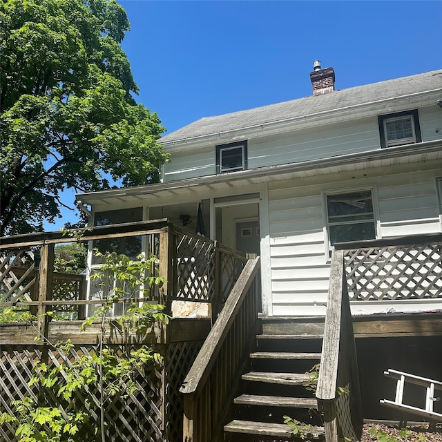 view of exterior entry featuring a chimney and a deck