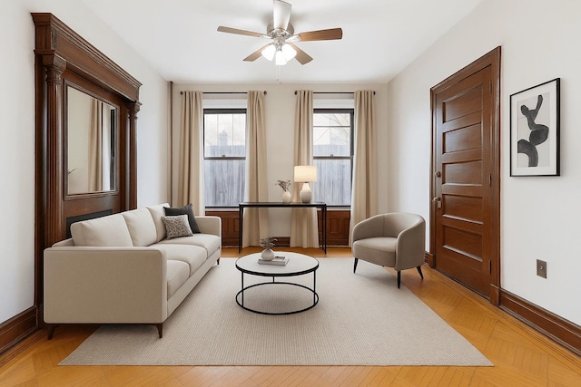 living area featuring a ceiling fan and baseboards