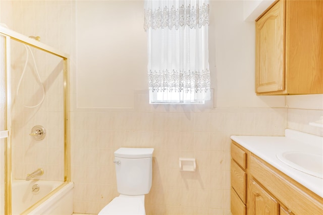 full bathroom with toilet, tile walls, vanity, shower / bathtub combination, and a wainscoted wall