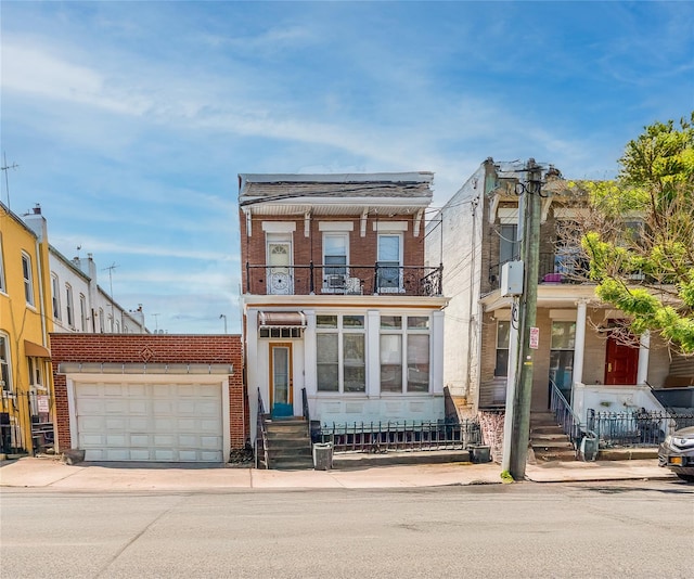 view of property with a balcony, brick siding, and driveway