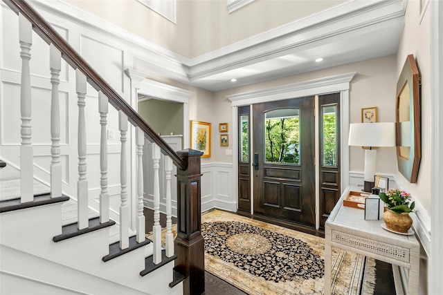 entrance foyer with a decorative wall, wainscoting, stairs, recessed lighting, and wood finished floors