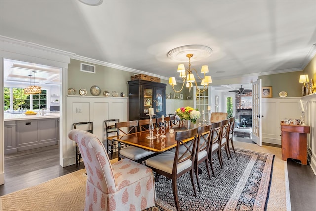 dining room with a decorative wall, a chandelier, ceiling fan, ornamental molding, and a wainscoted wall
