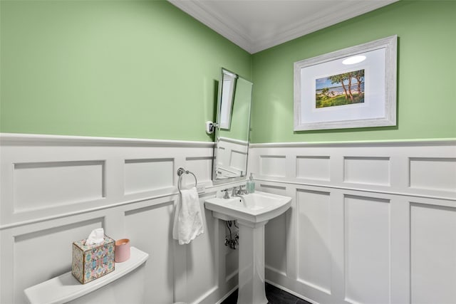 half bath with a decorative wall, ornamental molding, wainscoting, and toilet