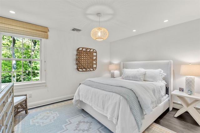 bedroom featuring baseboards, recessed lighting, wood finished floors, and a baseboard heating unit