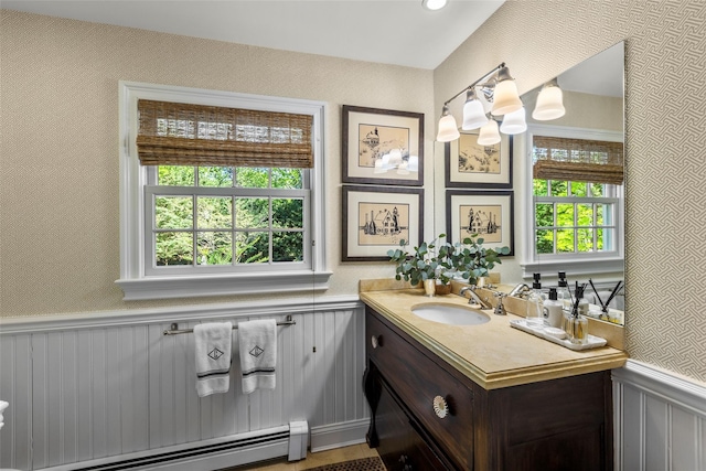 bathroom with a baseboard heating unit, a wainscoted wall, and vanity