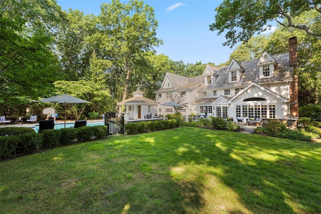 view of front of property with a chimney, a front yard, an outdoor pool, a patio area, and an outdoor living space