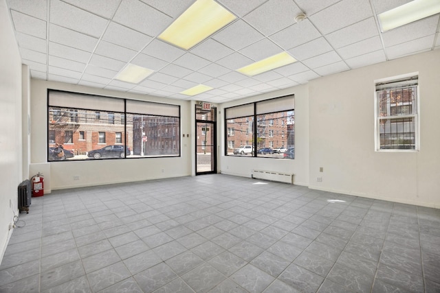 42-06 66th St, Woodside, NY 11377 - tiled empty room with a baseboard heating unit and a paneled ceiling