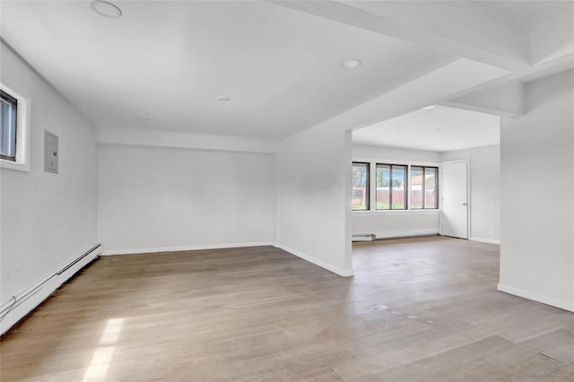 unfurnished room featuring baseboard heating, light wood-style floors, and baseboards