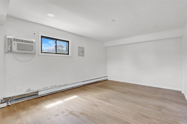 spare room featuring baseboard heating, wood finished floors, a wall mounted AC, and baseboards
