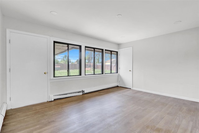 empty room with wood finished floors and baseboard heating