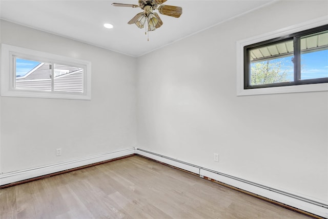 empty room featuring baseboard heating, wood finished floors, a ceiling fan, recessed lighting, and baseboards