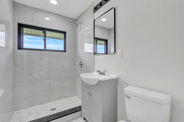 full bath featuring tiled shower, toilet, and vanity