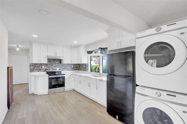 kitchen featuring stainless steel electric range oven, freestanding refrigerator, estacked washer and dryer, under cabinet range hood, and light countertops