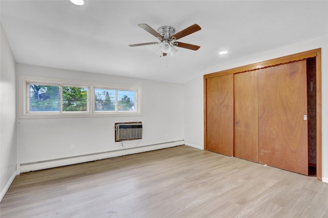 unfurnished bedroom with a baseboard radiator, an AC wall unit, light wood-type flooring, recessed lighting, and a closet