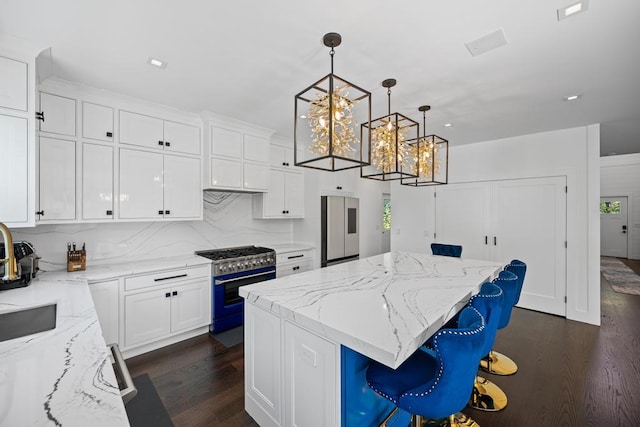 128 Priscilla Ave, Flanders, NY 11901 - kitchen with appliances with stainless steel finishes, dark wood-style flooring, a center island, a chandelier, and white cabinetry