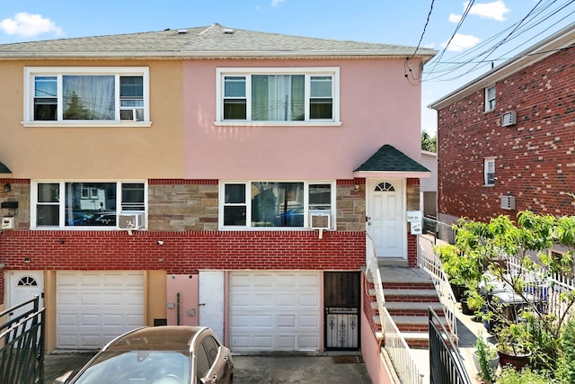 220-24 134th Rd, Laurelton, NY 11413 - view of property with an attached garage, stucco siding, a shingled roof, stone siding, and driveway