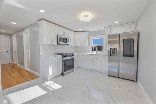 52 State St, Valley Stream, NY 11580 - kitchen with appliances with stainless steel finishes, baseboards, light countertops, white cabinetry, and recessed lighting