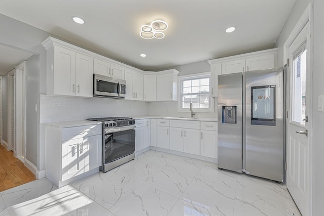 52 State St, Valley Stream, NY 11580 - kitchen with appliances with stainless steel finishes, a sink, light countertops, white cabinetry, and light marble finish flooring