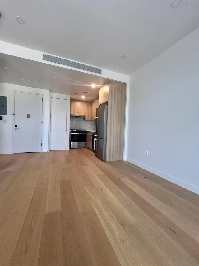 unfurnished living room with light wood-type flooring, baseboards, and electric panel