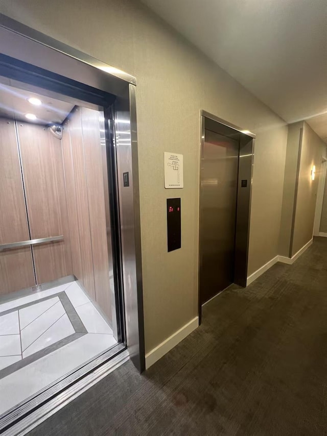 hallway with elevator, baseboards, and lofted ceiling