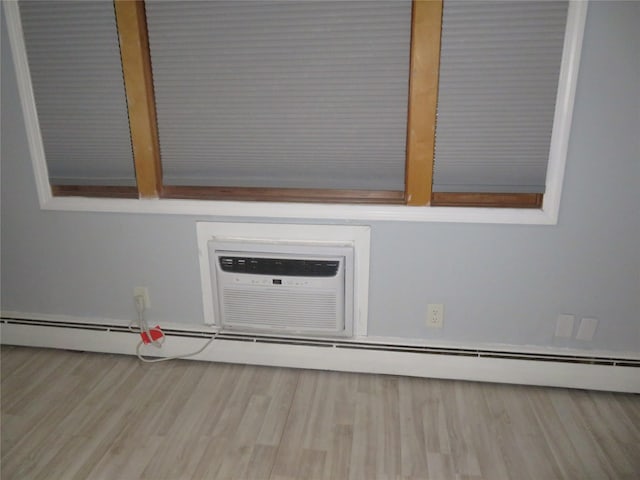 detailed view of wood finished floors, an AC wall unit, and a baseboard radiator