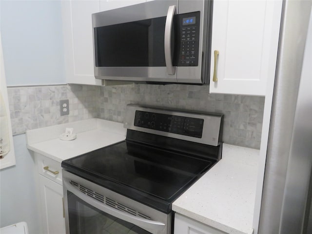 kitchen featuring stainless steel appliances, white cabinetry, and tasteful backsplash