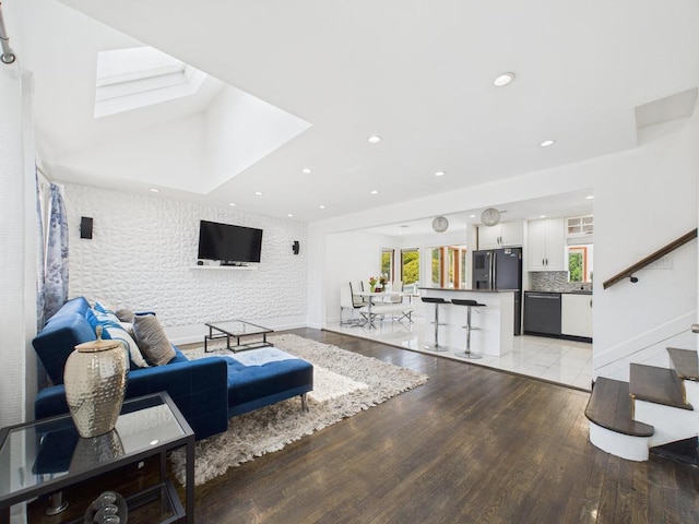 living room featuring light wood finished floors, a skylight, recessed lighting, and baseboards