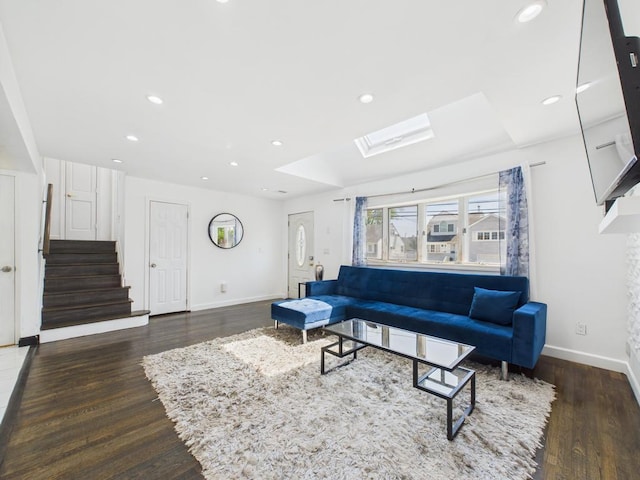 living room featuring baseboards, a skylight, wood finished floors, stairs, and recessed lighting