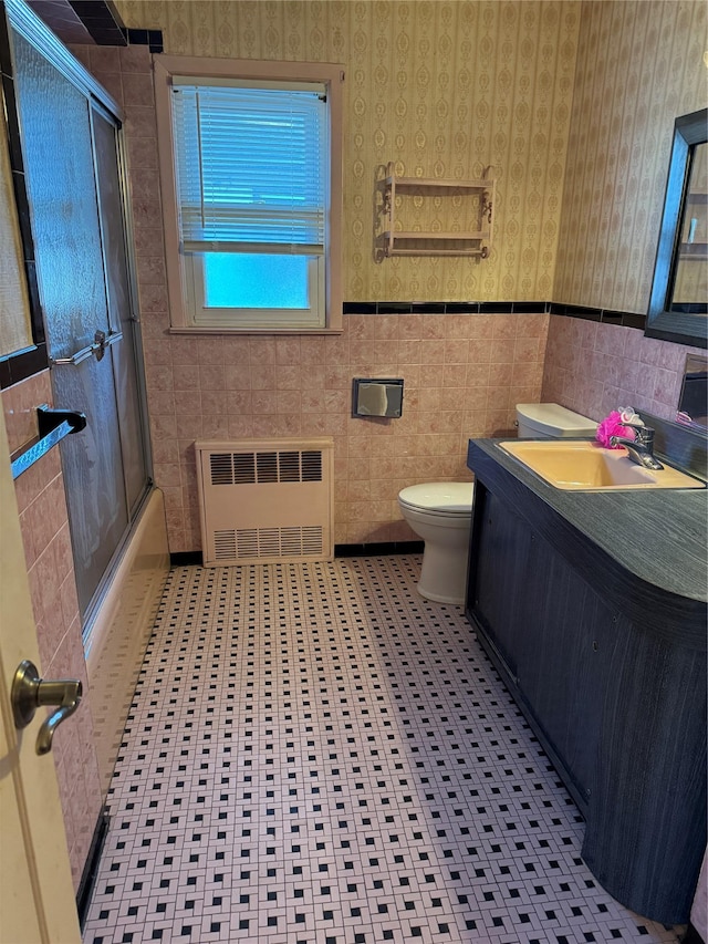 163-33 90th St, Howard Beach, NY 11414 - bathroom with radiator heating unit, wallpapered walls, toilet, vanity, and bath / shower combo with glass door