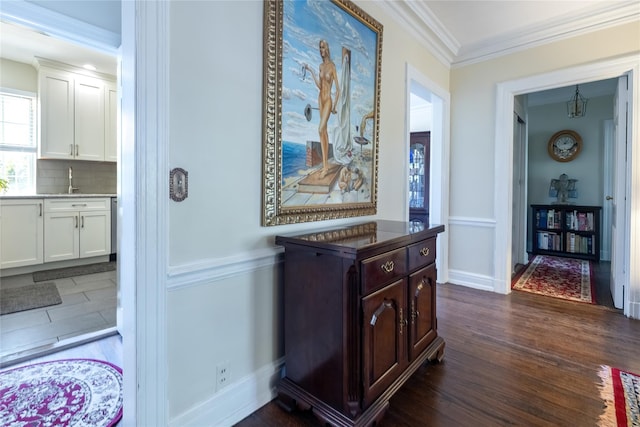 hallway featuring dark wood-type flooring, ornamental molding, baseboards, and a chandelier