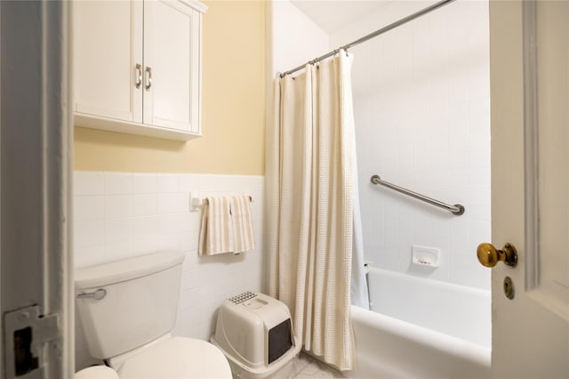 bathroom with tile walls, toilet, shower / bath combo with shower curtain, and a wainscoted wall