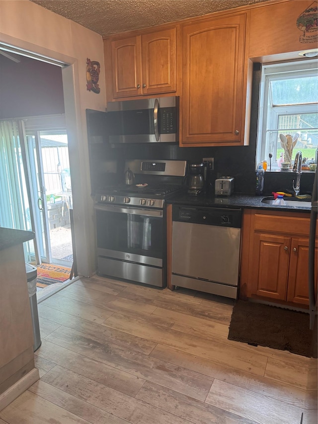 8 Windmill Ln, New City, NY 10956 - kitchen featuring stainless steel appliances, light wood finished floors, a sink, dark countertops, and brown cabinets