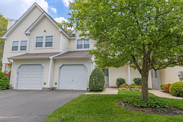 view of front of house featuring driveway, an attached garage, a chimney, and a front lawn