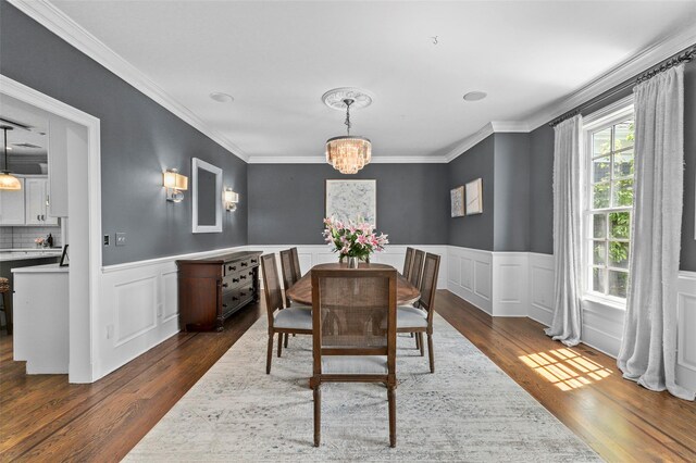 2 Cerf Ln, Mount Kisco, NY 10549 - dining space featuring dark wood-style floors, ornamental molding, a chandelier, a wainscoted wall, and a decorative wall
