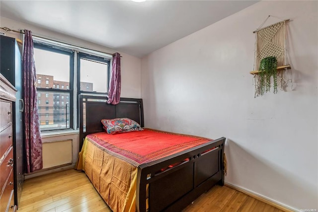 bedroom featuring hardwood / wood-style flooring, multiple windows, and baseboards