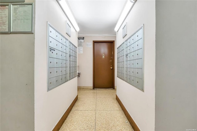 corridor with dark aggregate flooring, mail area, and baseboards