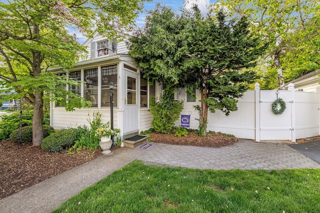 view of front of home with a sunroom and fence
