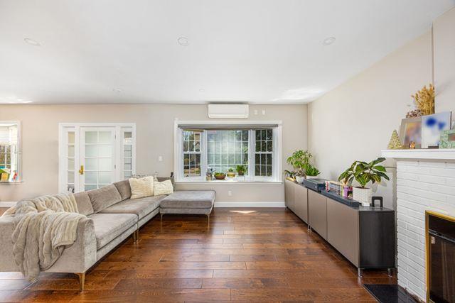 7203 Ingram St, Forest Hills, NY 11375 - living area with dark wood-style flooring, a wall unit AC, a fireplace, and baseboards