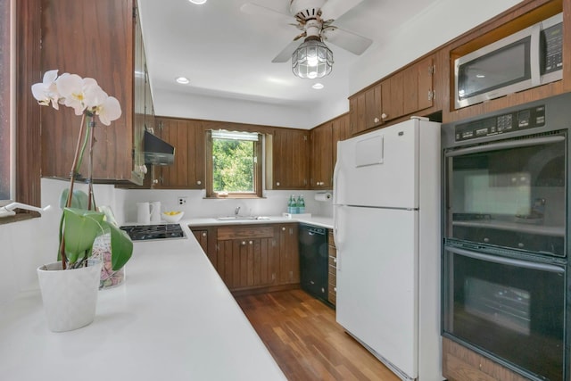 40 Brookby Rd, Scarsdale, NY 10583 - kitchen with black appliances, under cabinet range hood, light countertops, a sink, and dark wood-type flooring