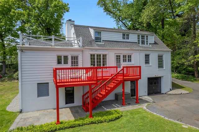 40 Brookby Rd, Scarsdale, NY 10583 - rear view of property with a shingled roof, a chimney, a wooden deck, an attached garage, and asphalt driveway