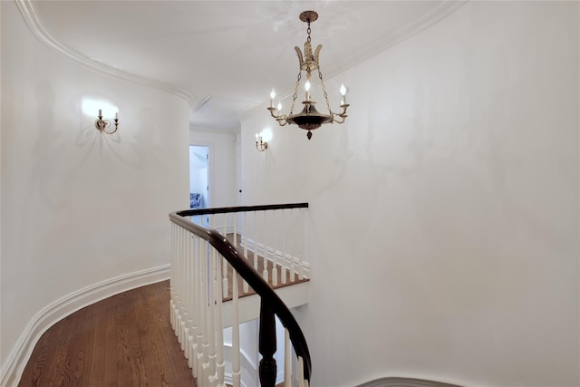 hallway with an upstairs landing, wood finished floors, a chandelier, and ornamental molding