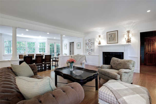 living room with decorative columns, crown molding, a premium fireplace, wood finished floors, and recessed lighting