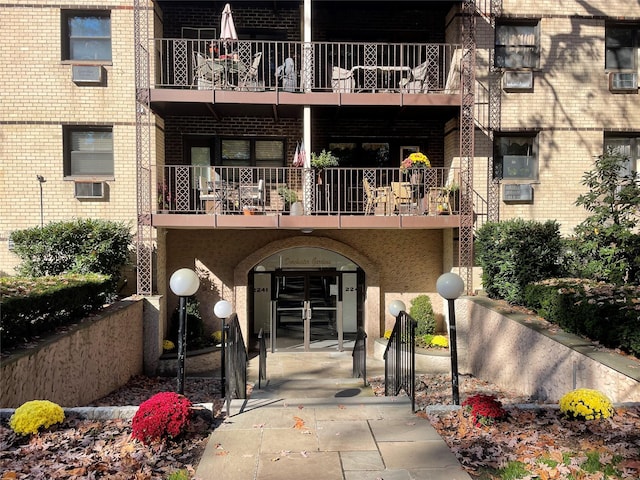 doorway to property with a balcony, brick siding, and cooling unit