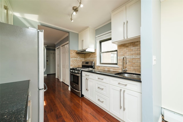 kitchen featuring stainless steel gas range oven, a sink, freestanding refrigerator, tasteful backsplash, and ornamental molding