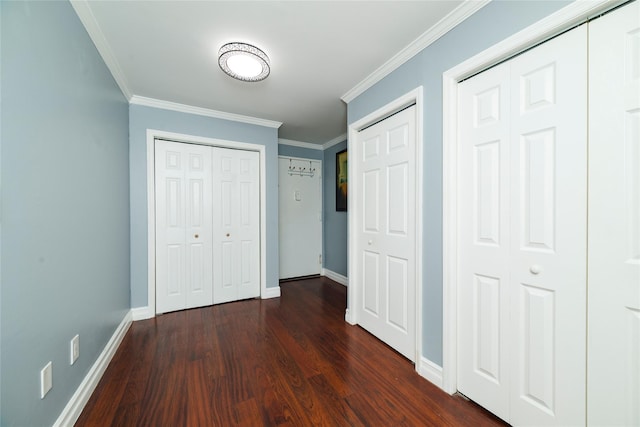 unfurnished bedroom featuring baseboards, dark wood finished floors, ornamental molding, and two closets