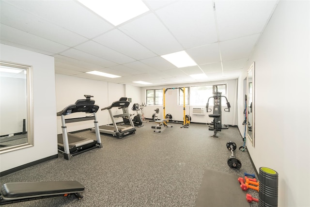gym featuring a paneled ceiling, baseboards, and a wall mounted air conditioner