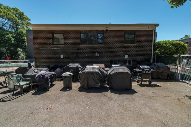 back of house featuring brick siding, fence, and a patio area