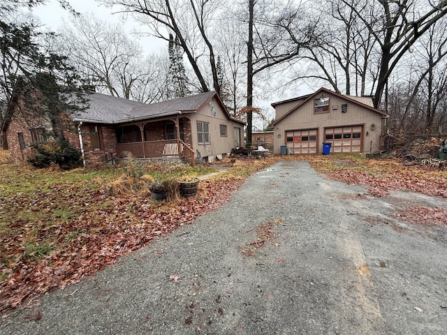 47 River Ln, Bloomingburg, NY 12721 - view of property exterior featuring a porch, an outdoor structure, a detached garage, asphalt driveway, and brick siding
