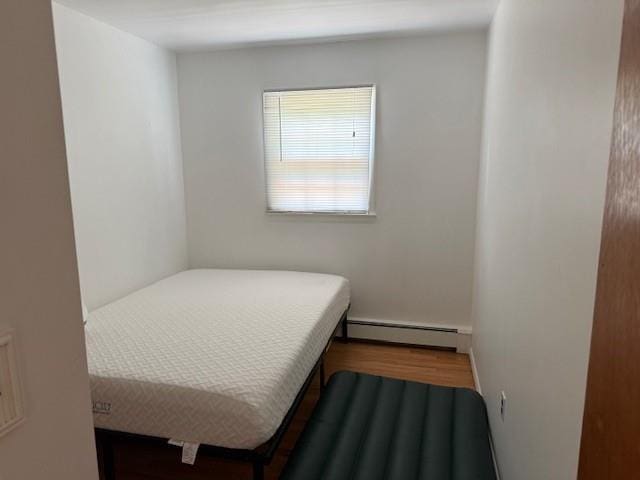 bedroom featuring baseboard heating and wood finished floors